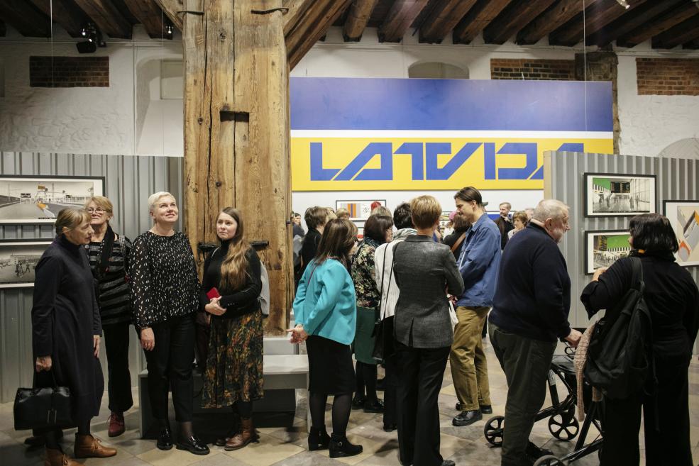 Visitors at the opening of the exhibition near the inscription "Latvija".