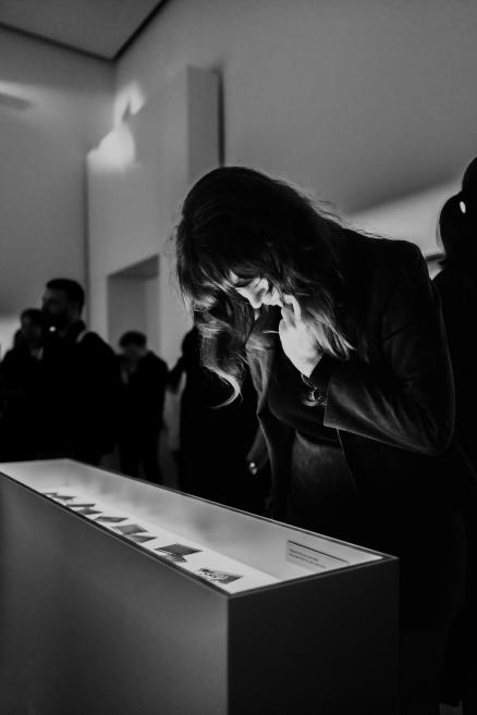 Black and white image of a visitor at a showcase at an exhibition.