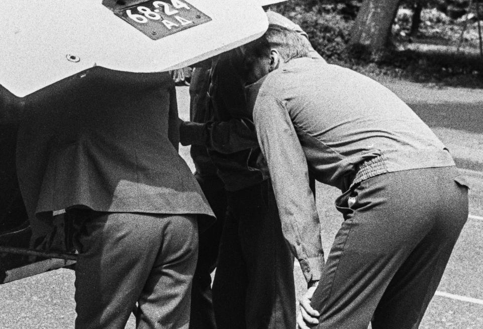 Black and white image of men inspecting a car.