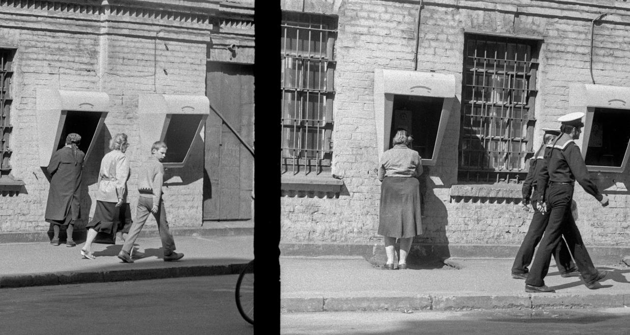 Black and white image of a woman at a phone booth.